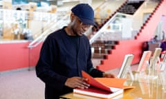 Cambridge, MA -- Writer and photographer Teju Cole looks at a book at the Cambridge Public Library, where he often visits to research and write, on October 2, 2023, in Cambridge, Massachusetts. (photo by Kayana Szymczak for The Observer)