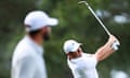 Rory McIlroy plays a shot on the 14th as Scottie Scheffler watches on