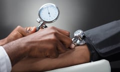 Close-up Of Male Doctor Measuring The Blood Pressure Of Patient Against Gray Background<br>M6JJK4 Close-up Of Male Doctor Measuring The Blood Pressure Of Patient Against Gray Background