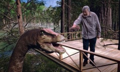 Image of Stephen standing on a platform in the trees, attempting to feed a Diplodocus hay