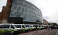 The exterior of a hospital with ambulances lined up in front.