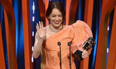 Emma Stone waves from the stage as she holds her Bafta award