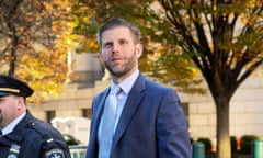 White man in suit walks with trees in background.