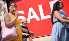 Shoppers on busy high street with sale sign in window