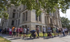 People line up on a summer day around a historic building.