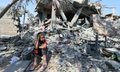 A child sits on rubble after a house was destroyed by an Israeli strike.