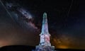 A monument is lit up at night with Milky Way stars in the night sky