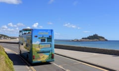 open top double decker passing sea and island with church