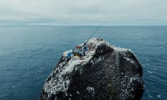 drone image of rock with camping bod and men on it