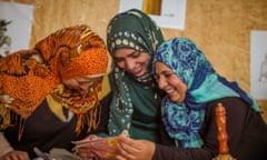 Female refugees looking at embroidery