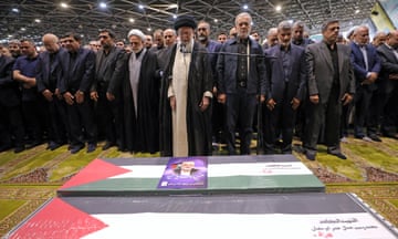 Iranian supreme leader Ayatollah Ali Khamenei leading a prayer, next to Iranian President Masoud Pezeshkian (C-R), as they stand over the coffin of late Hamas leader Ismail Haniyeh and his bodyguard, during his funeral procession in Tehran on August