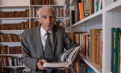 martin rees standing by his bookshelves holding an open book