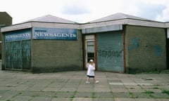 Small girl walking past boarded up shops on run down estate