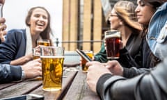 Hanging out with a fresh beer in a London Pub<br>Group of friends hanging out in a London Pub seated on the outdoor tables. Their drinking a mix of blonde and red beers and holding smartphones toasting together.