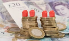 monopoly red house figures on a stack of pound coins atop a bed of sterling bank notes