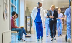 sales person at the hospital<br>a mid adult male doctor speaks with a businesswoman , sales person on the hospital corridor as they head to a meeting  ,with a young female nurse and patients in the busy corridor .