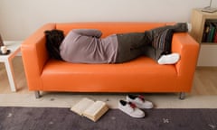 Man lies sleeping on sofa with back to book on floor