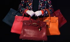 person holds five handbags of different colors, draped over her arms and in her hands. her head is not in the pic