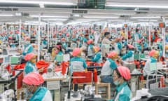 Hundreds of workers, identically clad, operate sewing machines at a garment factory