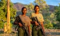 The two women holding sophisticated looking rifles against the backdrop of the beautiful national park