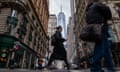 Shot from ground in middle of urban street, pedestrians in cold-weather clothing walk between high rises.