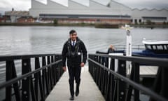 Rishi Sunak walks up a dockyard ramp wearing a buoyancy aid.