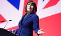 Rachel Reeves giving a speech on stage in front of a giant union flag projection