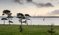 The sunset silhouettes the industrial towers of Esso’s Fawley oil refinery and trees in Netley Country Park on the shores of Southampton Water.<br>K6M504 The sunset silhouettes the industrial towers of Esso’s Fawley oil refinery and trees in Netley Country Park on the shores of Southampton Water.