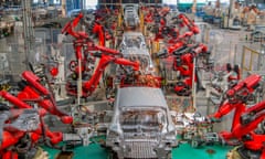 Red-coloured robotic arms work on the car assembly line of new energy vehicles at a factory