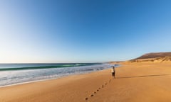 Clear sky over woman walking alone along Greenly beach, South Australia