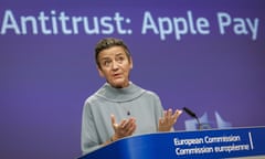 woman wearing grey gestures with hands in front of podium and small microphone