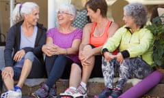 Four women, in their 50s, sitting in a row in yoga gear, and laughing together