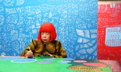 Yayoi Kusama at work in her studio, in front of her painting The Moving Moment When I Went to the Universe.