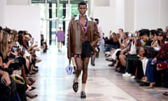 A model in short shorts carrying a handbag walks the runway at Gucci men’s spring/summer 2025 show during Milan Fashion Week.