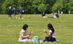 Two women enjoy a drink on the grass in Hyde Park, London