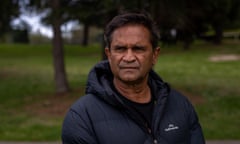 Nicky Winmar looks into the distance with a furrowed brow while standing in a park wearing a black puffer jacket