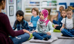 ▲ The Mental Health Foundation wants emotional wellbeing to sit at the heart of school curriculum photography: getty<br>A multi-ethnic group of young school children are indoors in their classroom. They are sitting on pillows and doing yoga together. They are sitting with their hands in their lap.
