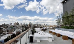 Public’s rooftop bar showing low-level white seating, with the city and dramatic cloudy sky in the background