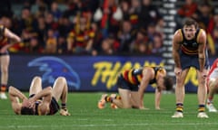 Adelaide Crows players slump on the pitch after losing