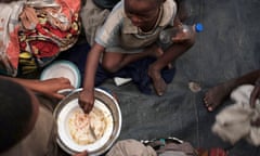 Two children eat from a bowl in a refugee camp in Burundi