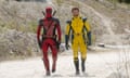 person in red and black suit and person in yellow and black suit walk side-by-side