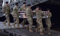 Soldiers in uniform carry a coffin on a ramp from a plane