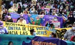 A crowd of women march along a street holding banners