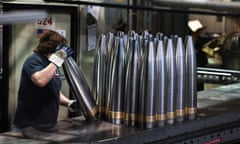 A worker handles artillery shells in a factory.