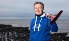 Rower Sian Davies posing by the sea with an oar held over her shoulder
