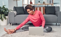 woman using a laptop while stretching in her living room