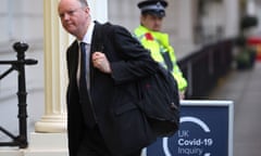 Chris Whitty with black rucksack passing police officer and sign that sayss UK Covid-19 Inquiry