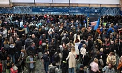 A large crowd of people stand on a concourse at Euston station