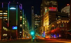 A clean, downtown street with high-rises lit by neon lights, and almost no traffic.