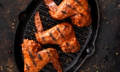 Barbecue grilled chicken wings in a cast iron griddle on a dark background